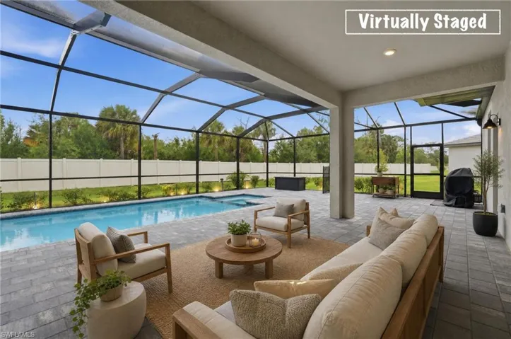Screened outdoor living area featuring a swimming pool, integrated spa, and paver patio