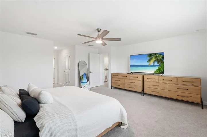 Spacious room featuring light gray carpet flooring, white painted walls, a ceiling fan with integrated lighting, and a doorway