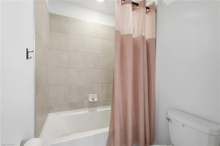 Second Floor- White porcelain bathtub with light-toned tiled surround