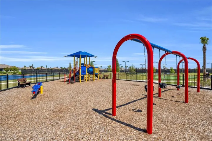 Community playground featuring a swing set, slide structure, and spring rider on a wood chip surface