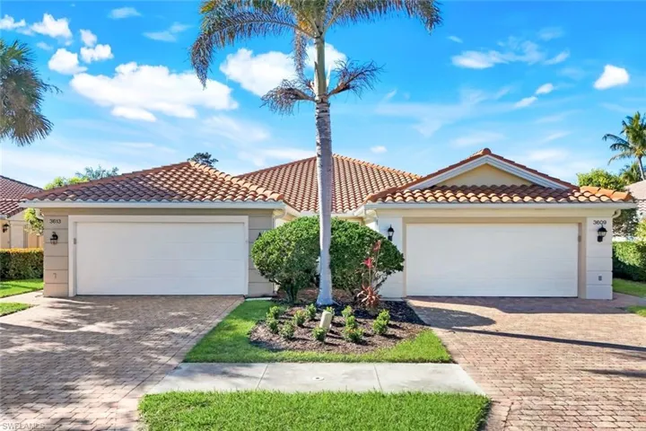 View of front facade featuring a tile roof, stucco siding, and decorative driveway