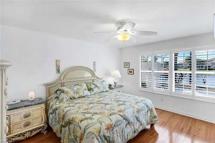 Bedroom featuring wood finished floors and ceiling fan with gorgeous lake view and Plantation shutters.