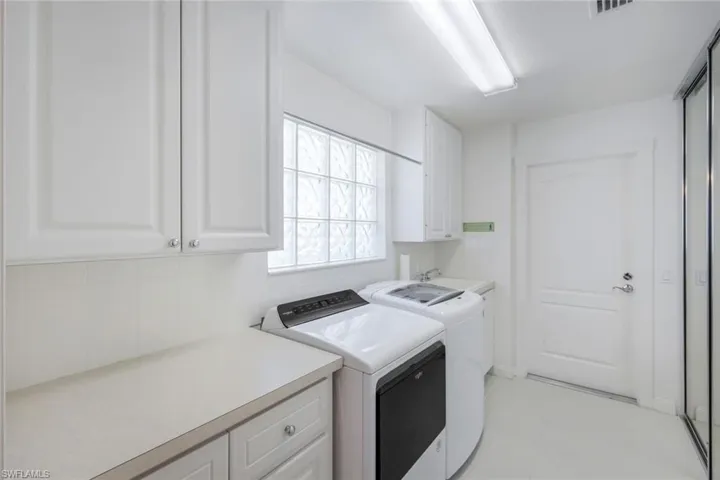 Laundry with utility sink, cabinet and closet space, washing machine and dryer, and light tile patterned floors
