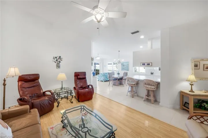 Living area with light wood-style floors, ceiling fan, and a chandelier