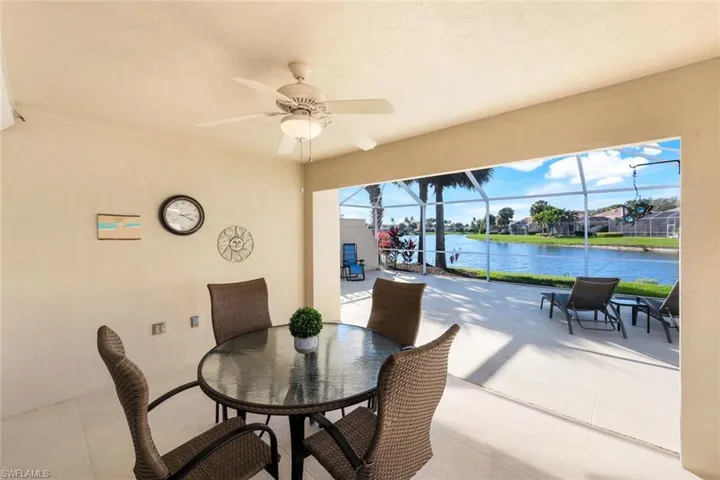 View of patio with lake view,  outdoor dining space and screened in lanai.