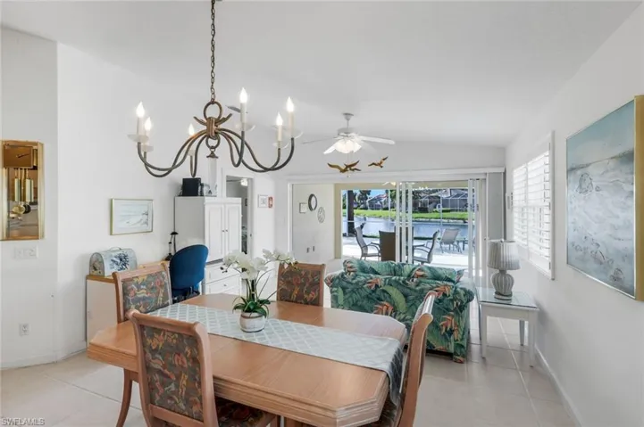 Dining room with a water view, lofted ceiling, light tile patterned floors, ceiling fan, and a chandelier