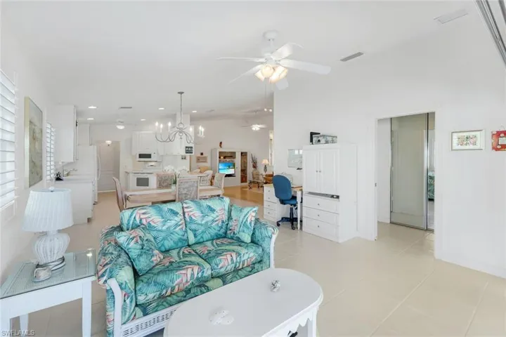 Living area with ceiling fan, a desk, recessed lighting, and light tile patterned flooring.