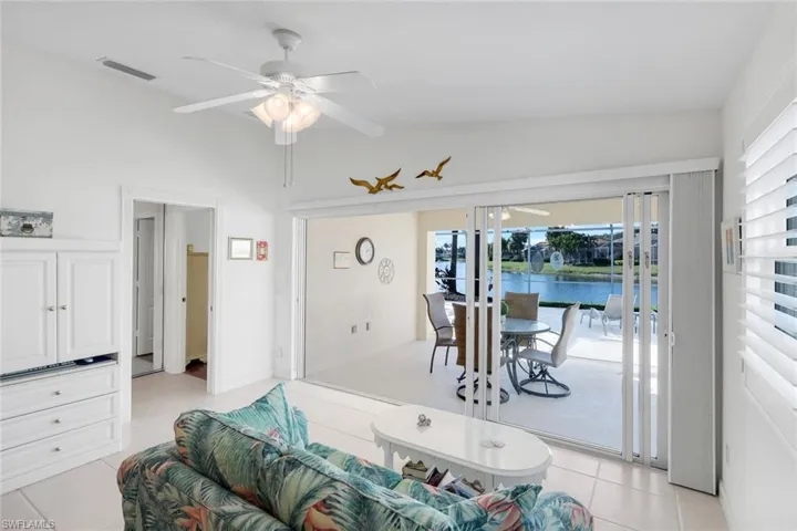 Water view, access to outside, light tile patterned floors, lanai and a ceiling fan