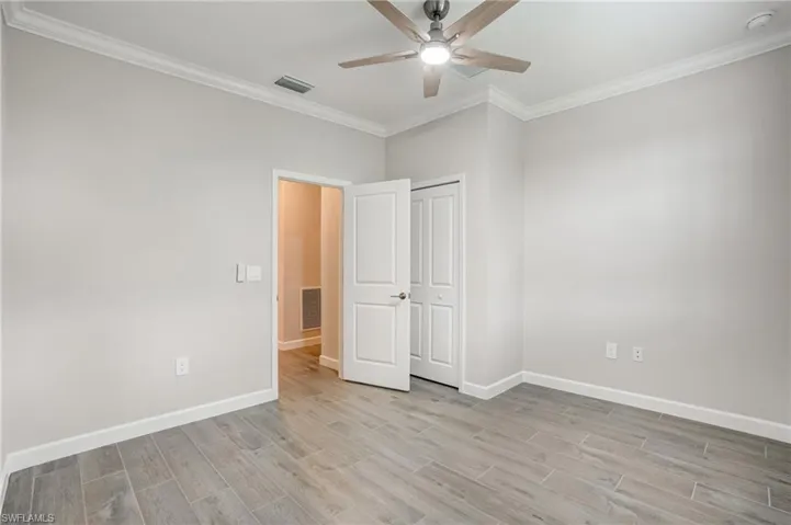 Unfurnished bedroom featuring light wood finished floors, ornamental molding, baseboards, a closet, and ceiling fan