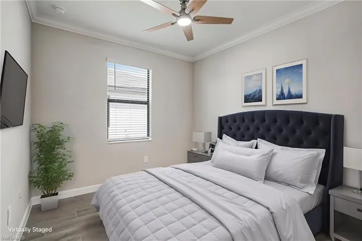 Bedroom featuring wood finished floors, crown molding, baseboards, and a ceiling fan