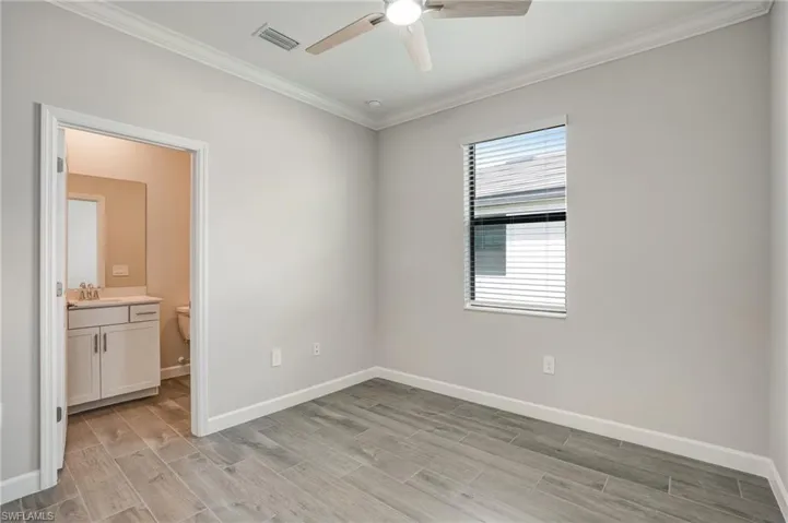Empty room with ceiling fan, ornamental molding, light wood-style flooring, baseboards, and a sink