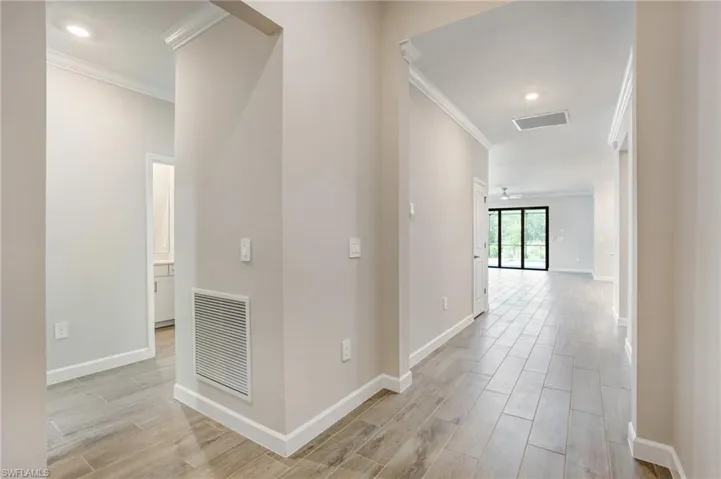 Corridor with crown molding, light wood finished floors, and baseboards