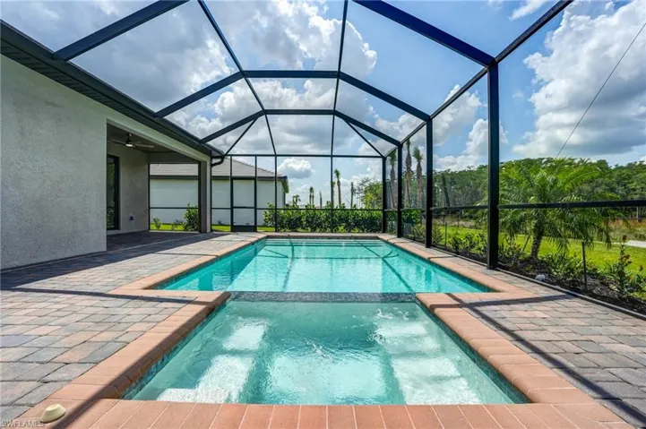 View of swimming pool with a pool with connected hot tub, a patio, and a lanai