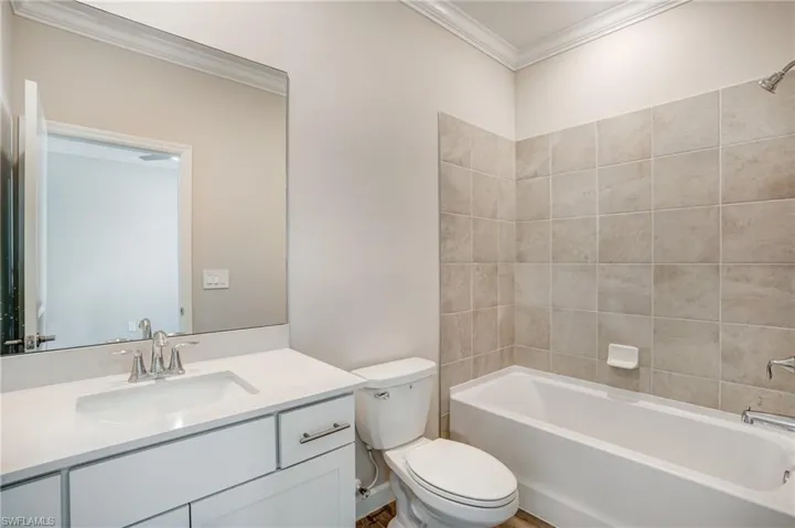Full bath featuring ornamental molding, toilet, vanity, and shower / bath combination