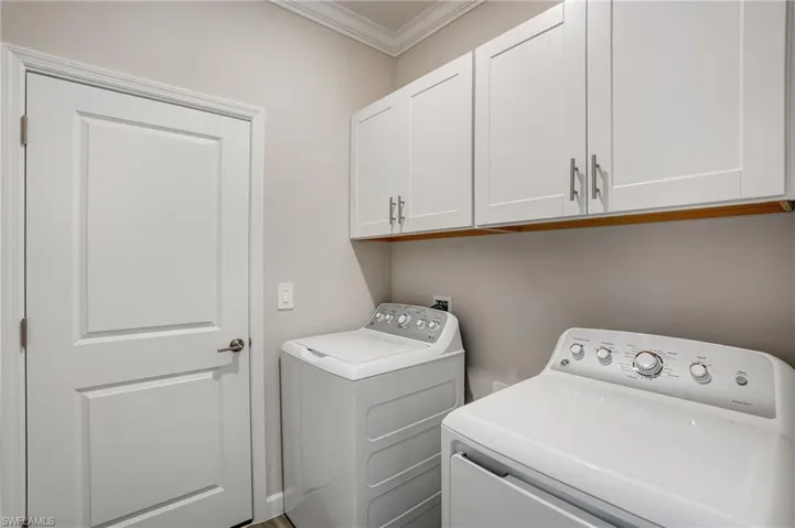 Washroom featuring cabinet space, washing machine and dryer, and crown molding