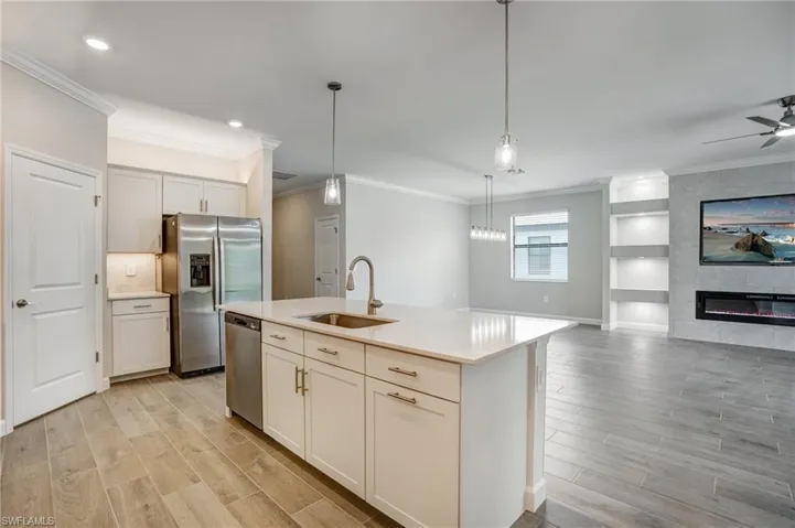 Kitchen featuring a sink, stainless steel appliances, light wood-style flooring, open floor plan, and crown molding
