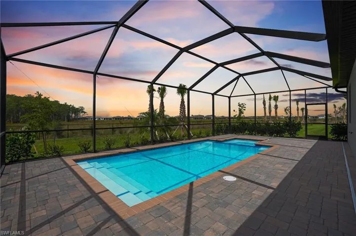 Pool at dusk with an outdoor pool and a patio