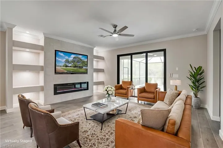 Living room with built in shelves, wood finished floors, ornamental molding, baseboards, and a ceiling fan