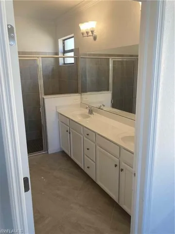 Bathroom featuring a dual vanity with white cabinetry, light-toned countertop, and undermount sinks
