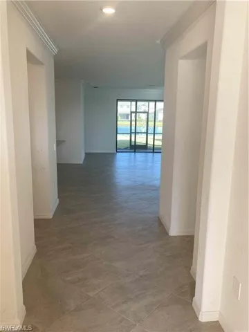 Open concept interior featuring large format tile flooring and crown molding