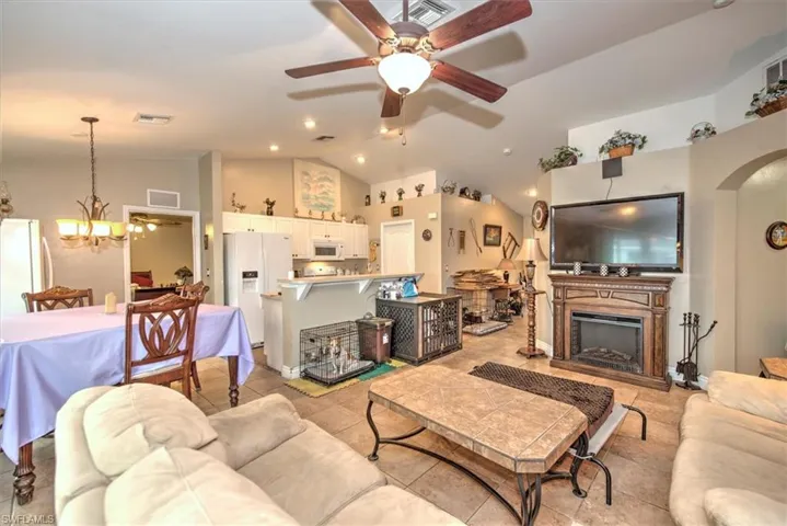 Living room featuring ceiling fan with notable chandelier and high vaulted ceiling