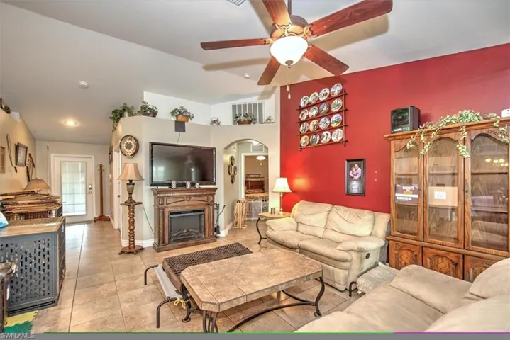 Tiled living room featuring ceiling fan and vaulted ceiling