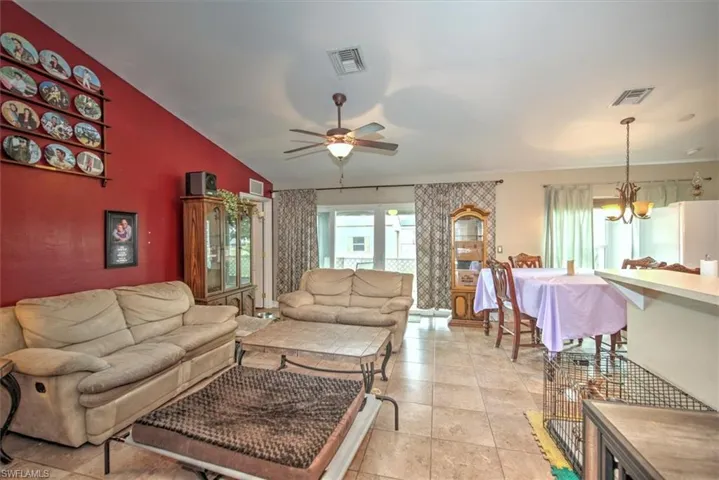 Living room featuring ceiling fan with notable chandelier and lofted ceiling