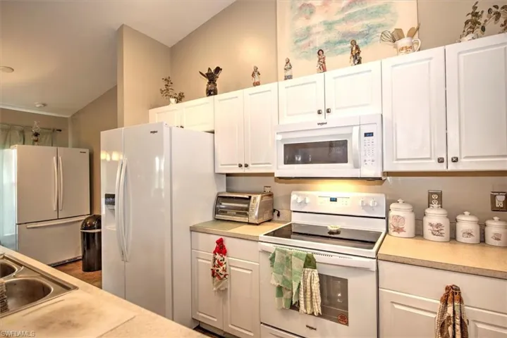 Kitchen featuring white cabinets, white appliances, and vaulted ceiling