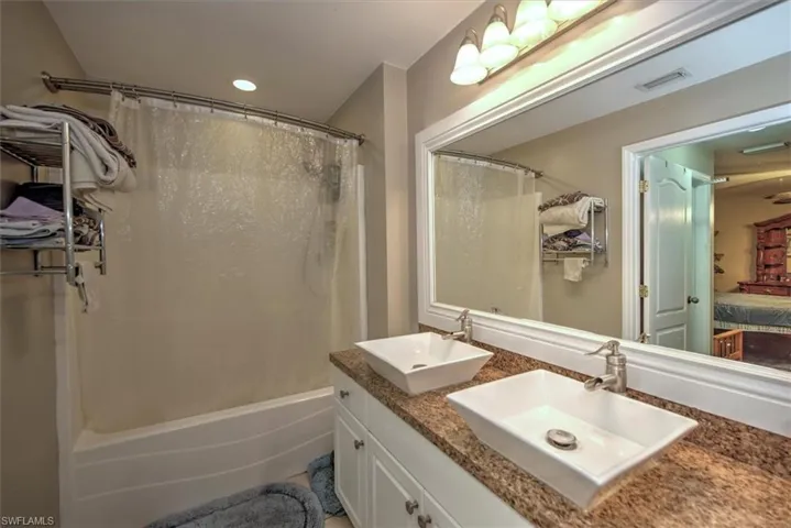 Bathroom featuring vanity and shower / bathtub combination with curtain