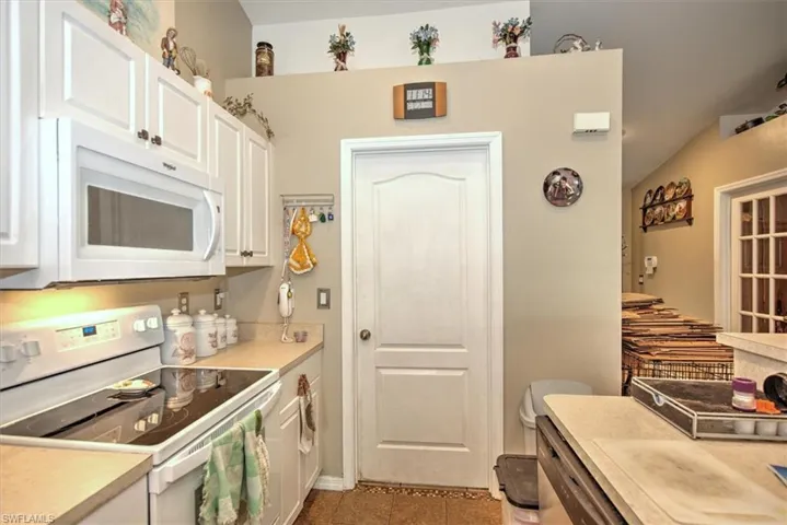 Kitchen featuring white appliances, white cabinetry, and tile patterned floors