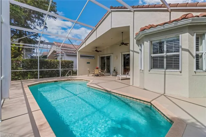 Pool featuring glass enclosure, a ceiling fan, and a patio area