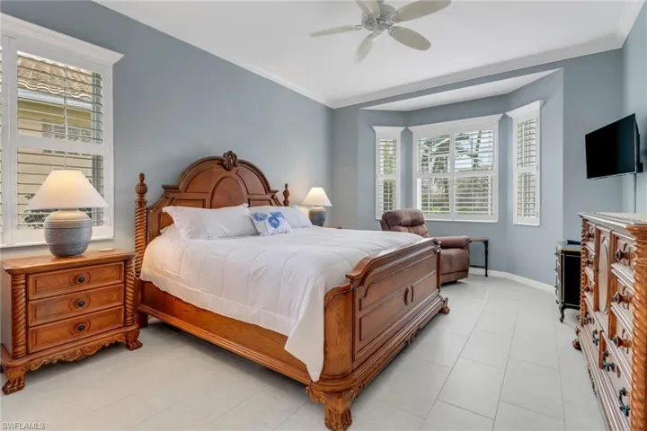 Bedroom featuring light tile patterned floors, crown molding, ceiling fan, and baseboards