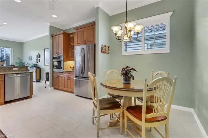 Kitchen with appliances with stainless steel finishes, stone countertops, hanging light fixtures, brown cabinets, and glass insert cabinets