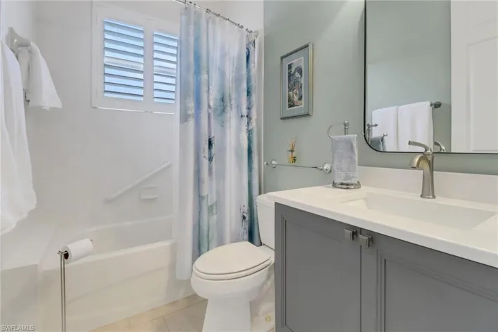Bathroom featuring vanity, shower / bathtub combination with curtain, toilet, and tile patterned floors