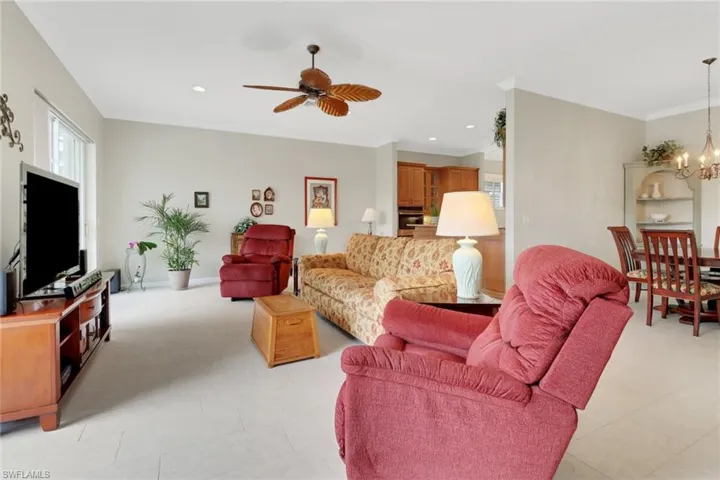Living area featuring ceiling fan with notable chandelier, crown molding, and recessed lighting