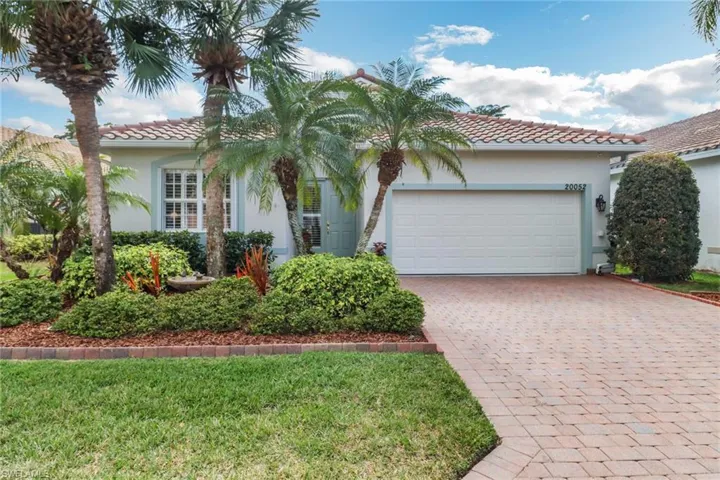 View of front facade featuring a tiled roof, stucco siding, decorative driveway, and a garage