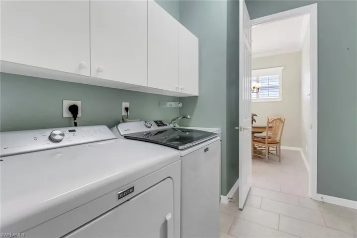 Laundry room with baseboards, washing machine and dryer, a sink, light tile patterned floors, and cabinet space
