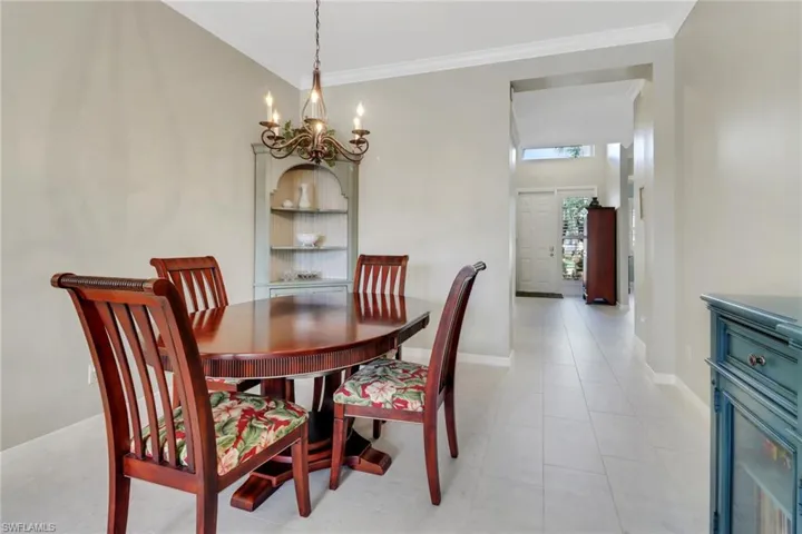 Dining room with baseboards, an inviting chandelier, ornamental molding, and light tile patterned flooring