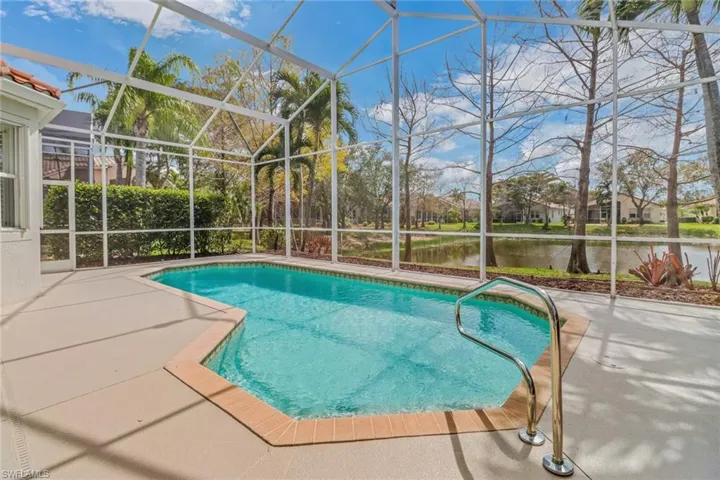 Pool featuring a water view, glass enclosure, and a patio