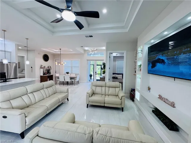Living area with a raised ceiling, a ceiling fan, and recessed lighting