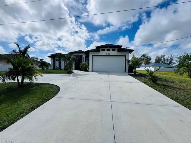 View of front of house with a front lawn, driveway, stucco siding, and an attached garage