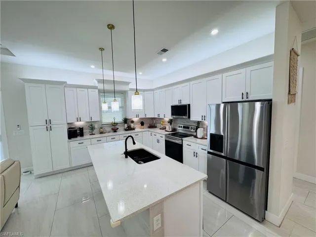 Kitchen featuring stainless steel appliances, white cabinets, light stone countertops, pendant lighting, and recessed lighting