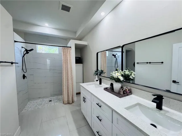 Full bathroom featuring double vanity, a stall shower, light tile patterned flooring, and recessed lighting