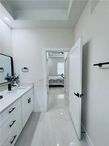 Bathroom with vanity, ensuite bathroom, a tray ceiling, and light tile patterned floors