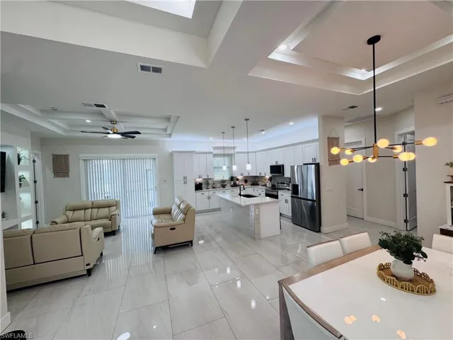 Dining area featuring a tray ceiling, ceiling fan, a chandelier, light tile patterned flooring, and recessed lighting