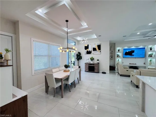 Dining room featuring a tray ceiling, a chandelier, and light marble finish flooring