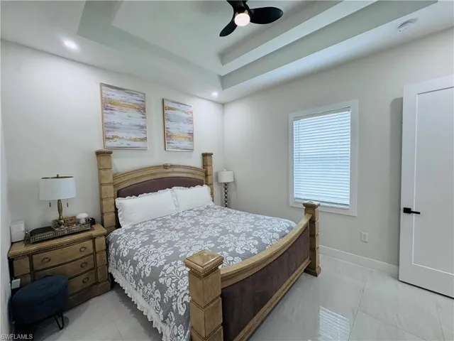 Bedroom featuring light tile patterned flooring, ceiling fan, and a raised ceiling