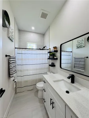 Bathroom with vanity, a shower with shower curtain, and light tile patterned floors