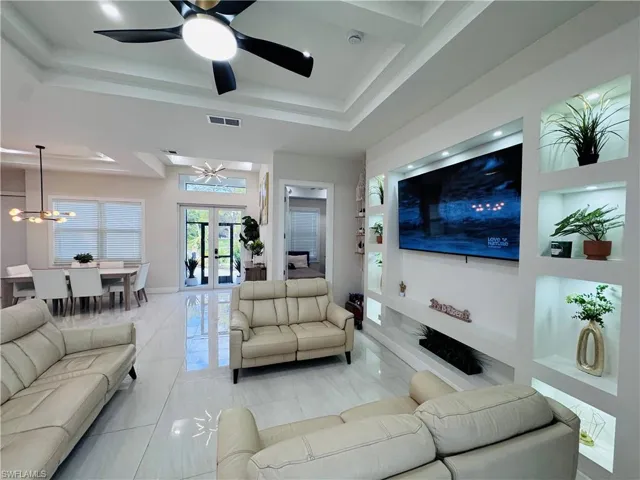 Living area with a raised ceiling, built in shelves, french doors, and a chandelier