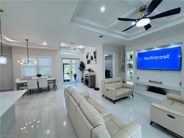 Living area featuring a ceiling fan, a chandelier, french doors, coffered ceiling, and beamed ceiling